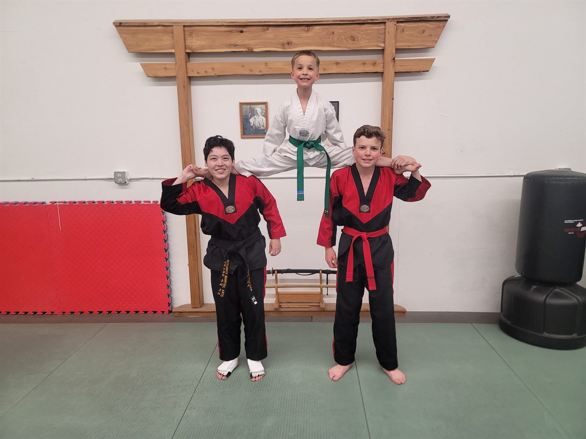 Three young Integrity Martial Arts students posing together at the dojang